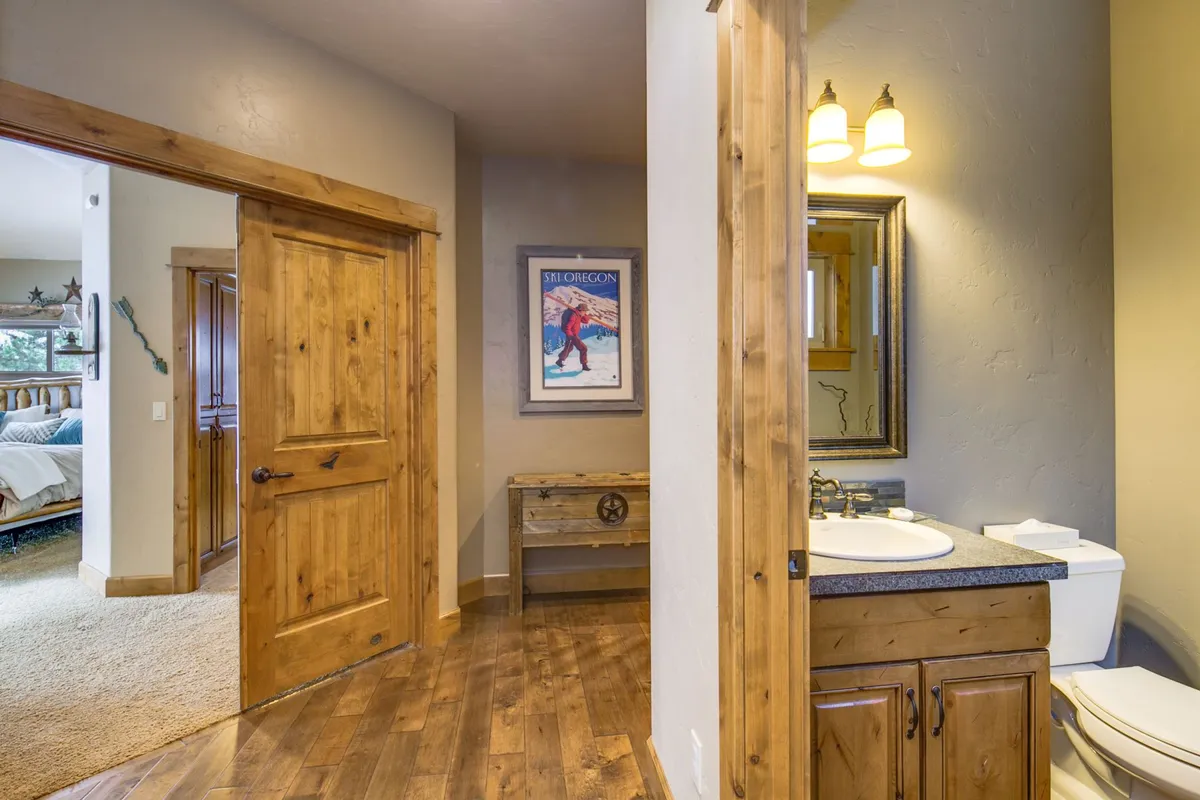 A private bathroom with a wooden door, vanity with sink, and framed artwork offers a welcoming environment for self-care and independence. The space feels both practical and inviting, aligning with the needs of younger guests.