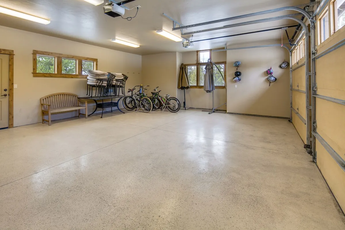 An interior garage space with cruiser bicycles neatly stored, a wooden bench, and outdoor gear organized on hooks. The space is practical and ready for adventure, highlighting secure bike storage and easy access for guests.